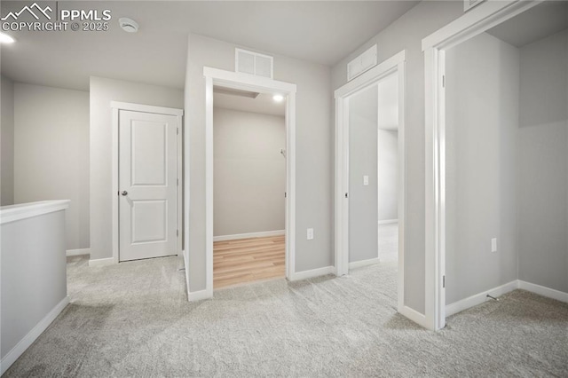corridor with baseboards, visible vents, and carpet flooring