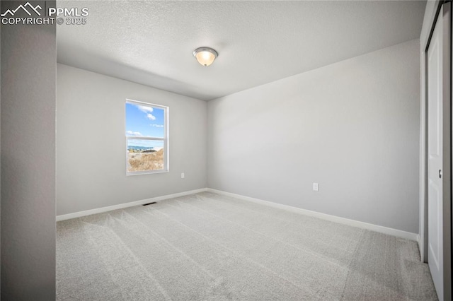 carpeted empty room with visible vents, baseboards, and a textured ceiling