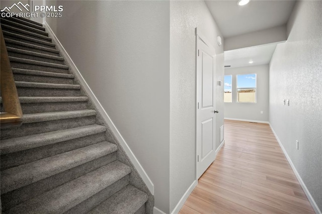 stairway featuring recessed lighting, a textured wall, baseboards, and wood finished floors