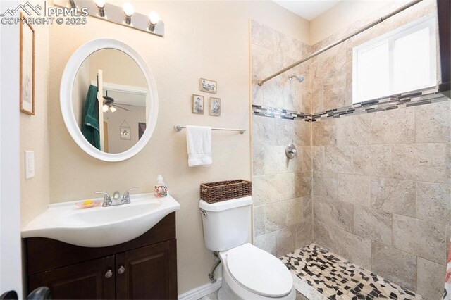 bathroom featuring vanity, a ceiling fan, tiled shower, and toilet