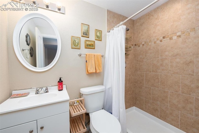 bathroom featuring a tile shower, toilet, and vanity