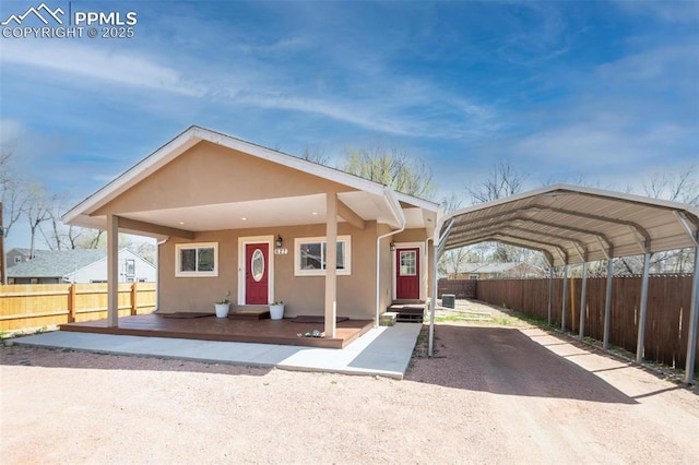 view of front of home featuring a detached carport, stucco siding, and fence