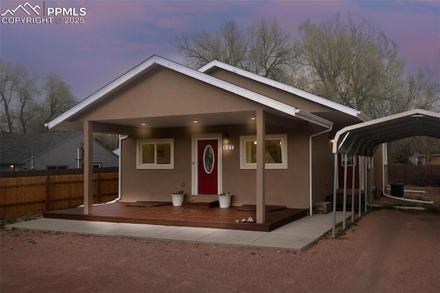 view of front of house with stucco siding, central AC unit, fence, and a detached carport