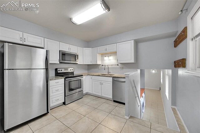 kitchen with white cabinets, stainless steel appliances, and light tile patterned floors