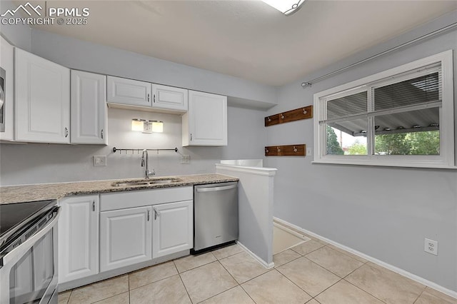kitchen featuring light tile patterned floors, stainless steel appliances, baseboards, a sink, and white cabinets