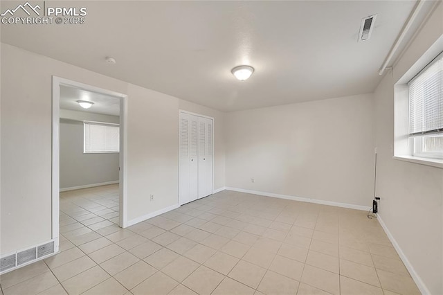 empty room featuring baseboards, visible vents, and light tile patterned floors