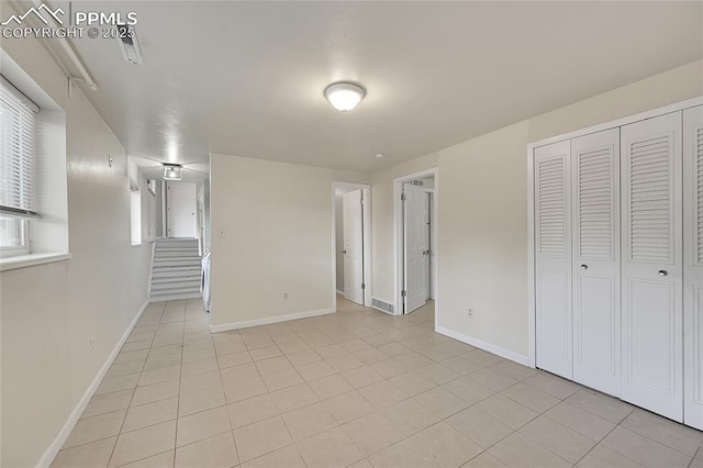 interior space featuring a closet, visible vents, baseboards, and light tile patterned floors