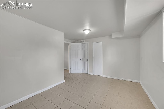 empty room featuring light tile patterned flooring, baseboards, and visible vents