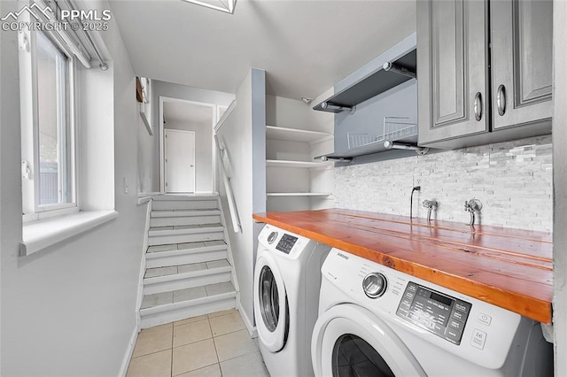 laundry area with light tile patterned flooring, cabinet space, baseboards, and washer and clothes dryer