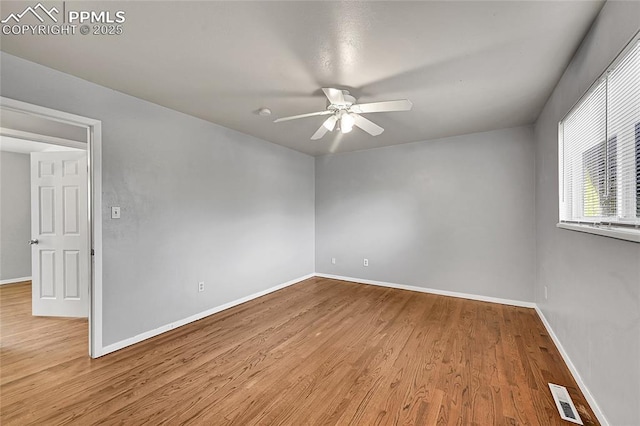 empty room featuring a ceiling fan, wood finished floors, baseboards, and visible vents