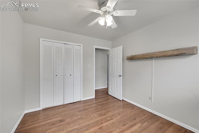 unfurnished bedroom with baseboards, a closet, wood finished floors, and a ceiling fan