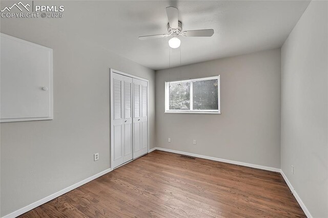unfurnished bedroom with baseboards, visible vents, a ceiling fan, a closet, and wood finished floors