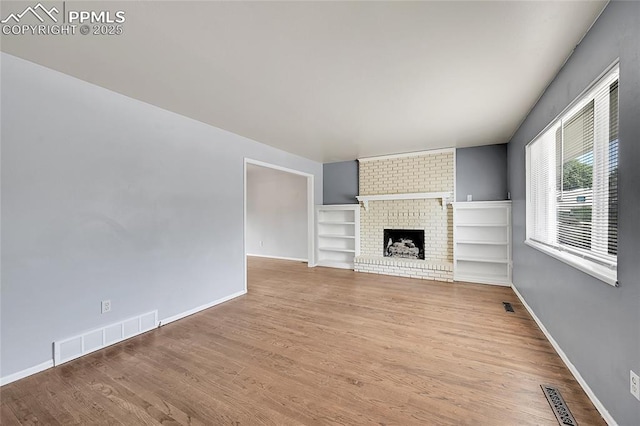 unfurnished living room with wood finished floors, baseboards, and visible vents