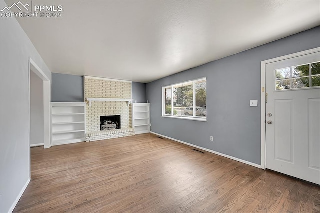 unfurnished living room featuring visible vents, baseboards, a fireplace, and wood finished floors