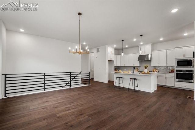 6678 Thimble Ct, Colorado Springs, CO 80924 - kitchen with appliances with stainless steel finishes, under cabinet range hood, white cabinets, dark wood-style flooring, and recessed lighting