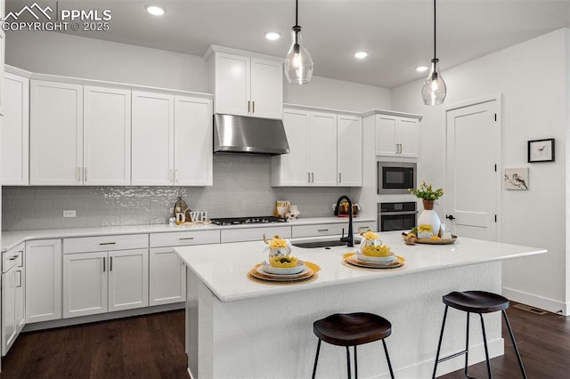 6678 Thimble Ct, Colorado Springs, CO 80924 - kitchen featuring under cabinet range hood, oven, gas stovetop, a sink, and a breakfast bar area