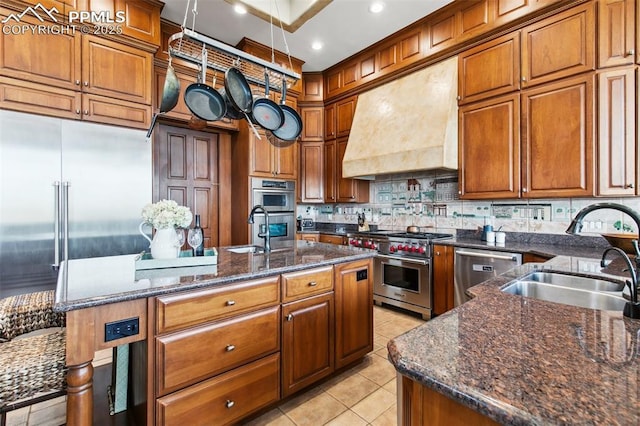 3870 S Club Dr, Colorado Springs, CO 80906 - kitchen with light tile patterned floors, brown cabinets, wall chimney exhaust hood, premium appliances, and a sink