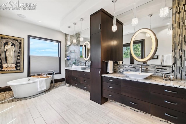 3870 S Club Dr, Colorado Springs, CO 80906 - full bathroom featuring a freestanding tub, a sink, recessed lighting, two vanities, and decorative backsplash