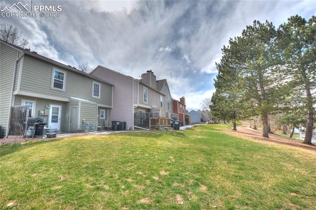 rear view of house with cooling unit, a residential view, a lawn, and a chimney