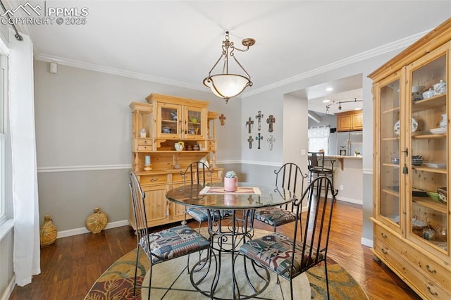 dining space with dark wood-style flooring, ornamental molding, and baseboards