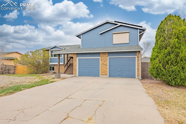 7775 Woody Creek Dr, Colorado Springs, CO 80911 - split level home with concrete driveway, fence, brick siding, a garage, and a shingled roof