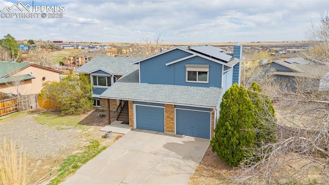 7775 Woody Creek Dr, Colorado Springs, CO 80911 - view of front of home with fence, an attached garage, solar panels, driveway, and a shingled roof