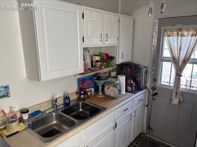 kitchen featuring light countertops, white cabinets, and a sink