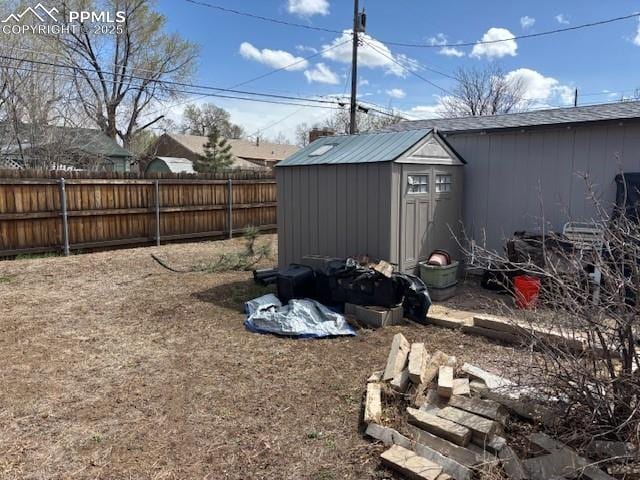 view of yard with a fenced backyard, an outbuilding, and a storage shed