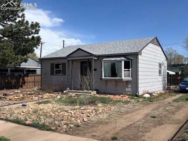 bungalow-style house featuring roof with shingles and fence