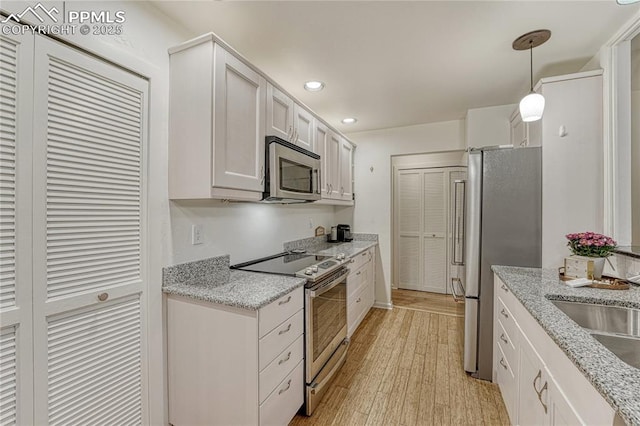 2372 Wood Ave, Colorado Springs, CO 80907 - kitchen with white cabinetry, light wood finished floors, recessed lighting, and appliances with stainless steel finishes