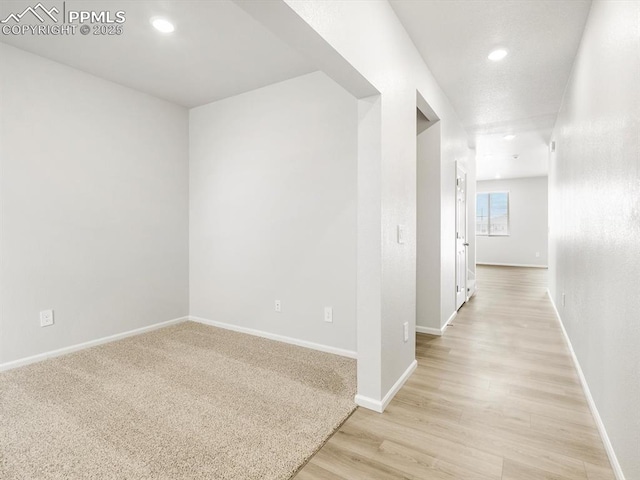 corridor featuring light wood-style flooring, baseboards, and recessed lighting