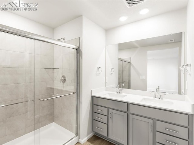 bathroom with double vanity, a sink, visible vents, and a stall shower