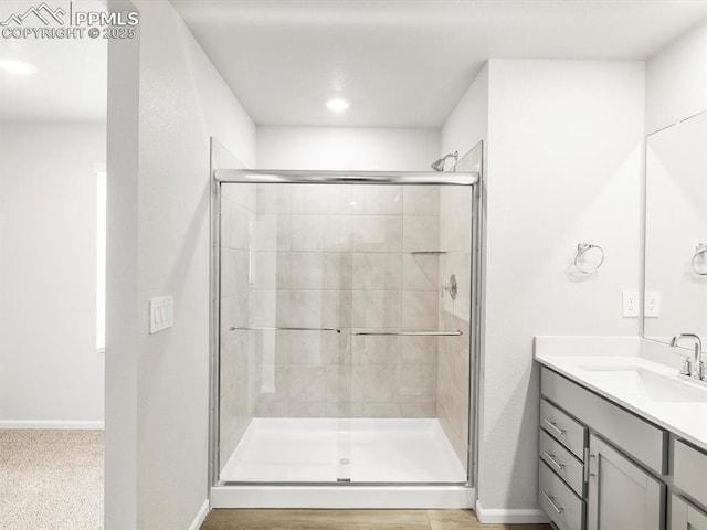 bathroom featuring baseboards, a shower stall, and vanity