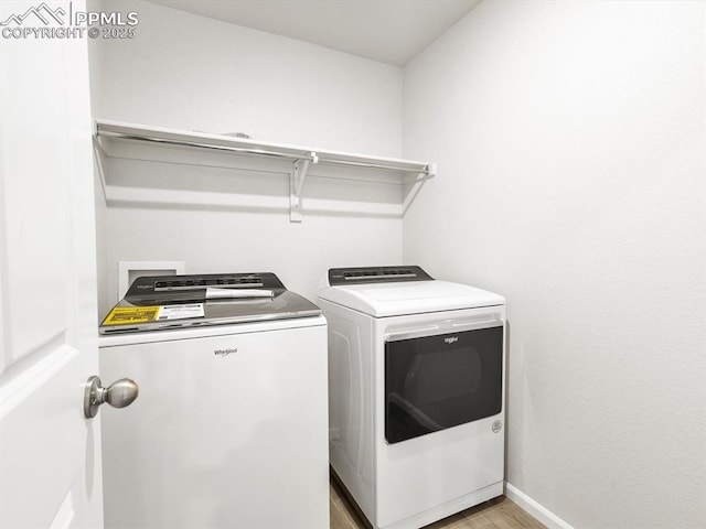 laundry room featuring baseboards, light wood finished floors, separate washer and dryer, and laundry area