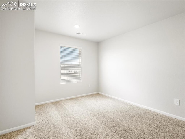 carpeted spare room with visible vents and baseboards