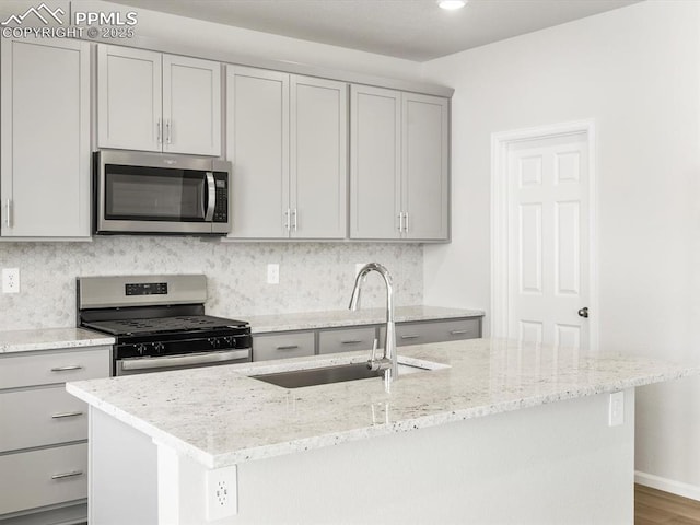 kitchen with stainless steel appliances, gray cabinetry, a sink, and tasteful backsplash