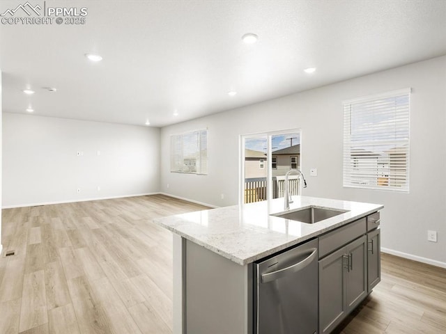 kitchen featuring a sink, light stone countertops, dishwasher, light wood finished floors, and gray cabinetry