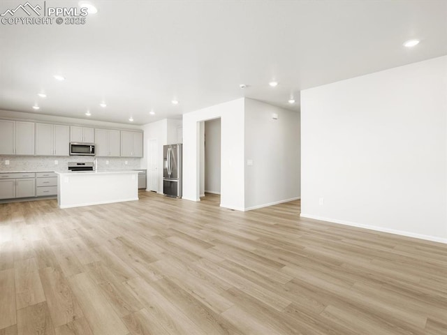 unfurnished living room featuring light wood-type flooring, baseboards, and recessed lighting