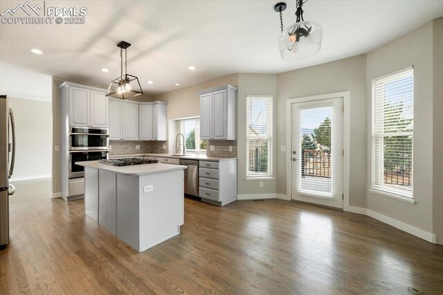 15110 Copperfield Dr, Colorado Springs, CO 80921 - kitchen featuring a center island, wood finished floors, a sink, stainless steel appliances, and decorative backsplash