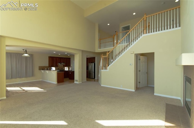 9443 St George Rd, Peyton, CO 80831 - unfurnished living room with baseboards, a high ceiling, stairs, a tile fireplace, and light carpet