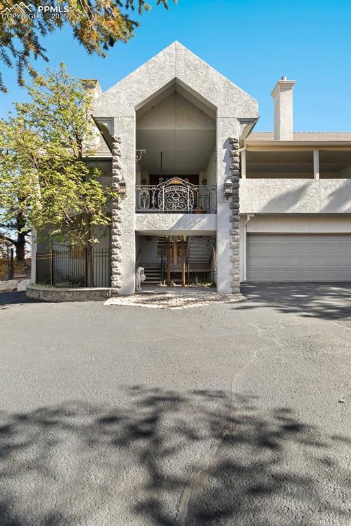 714 Southern Cross Pl, Colorado Springs, CO 80906 - view of front of property with a garage, a balcony, a chimney, and stucco siding