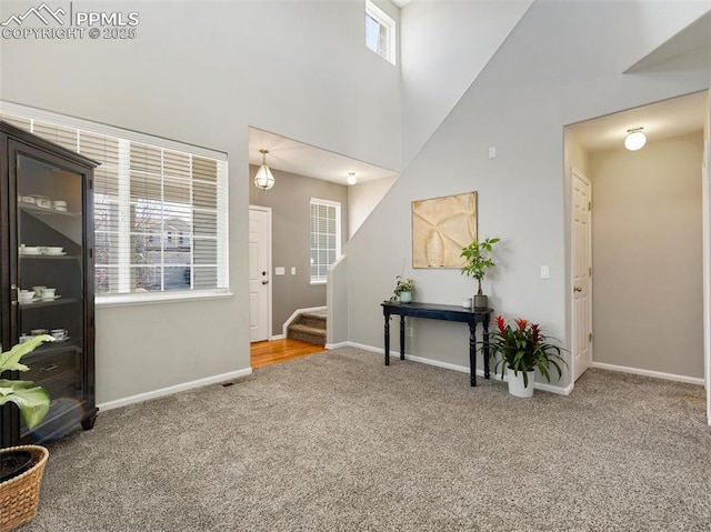foyer entrance with a high ceiling, carpet flooring, baseboards, and stairs