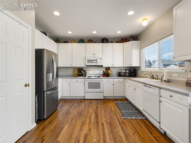 kitchen featuring a sink, white appliances, recessed lighting, white cabinetry, and wood finished floors