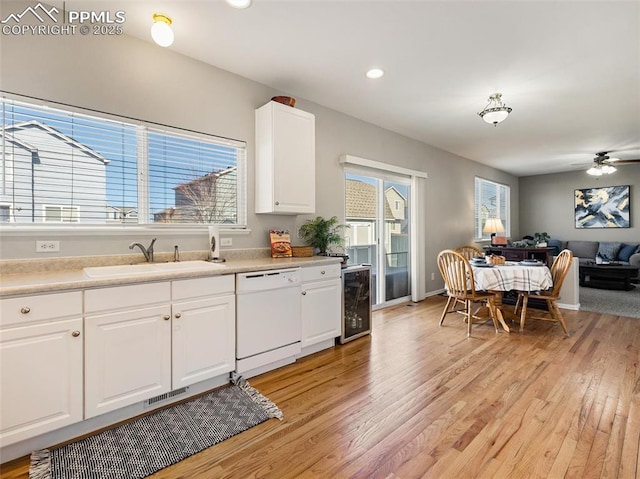 kitchen featuring light wood-style floors, a sink, beverage cooler, white dishwasher, and open floor plan