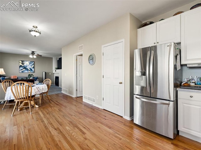 kitchen featuring stainless steel fridge with ice dispenser, white cabinets, open floor plan, light wood-type flooring, and a ceiling fan