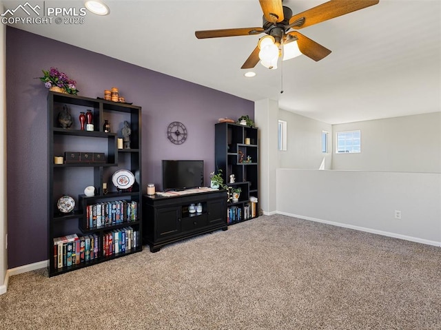 living room featuring carpet, baseboards, and ceiling fan
