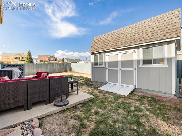 view of yard featuring a shed, a patio area, a fenced backyard, an outdoor living space, and an outbuilding