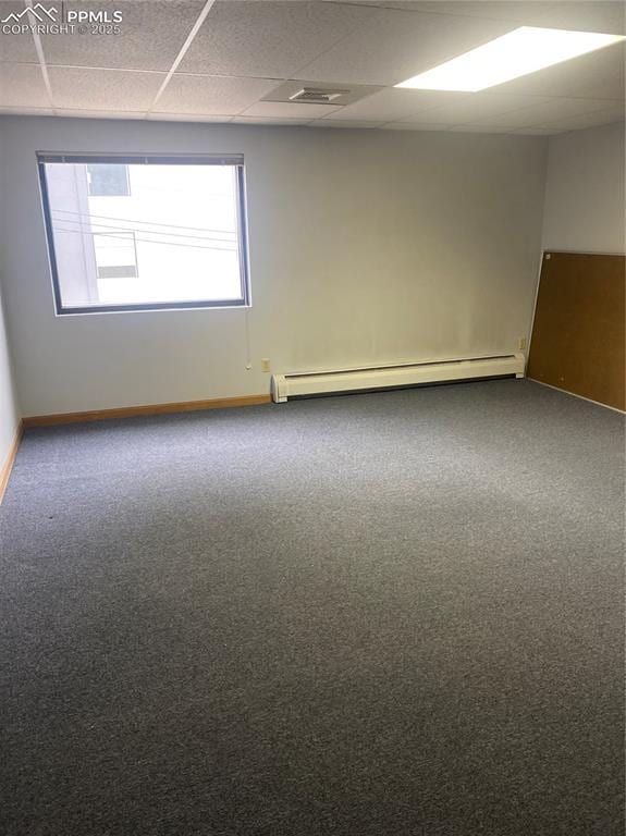 empty room with carpet floors, baseboards, and baseboard heating