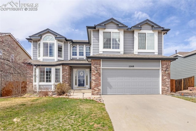 traditional home with brick siding, an attached garage, fence, and concrete driveway