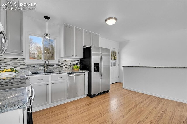 2518 Royalty Ct, Colorado Springs, CO 80904 - kitchen with decorative backsplash, a sink, pendant lighting, light wood finished floors, and appliances with stainless steel finishes